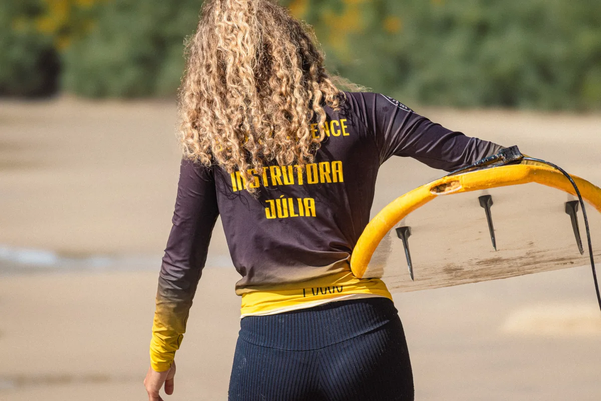 Aula de surf avulsa Village Summer — instrutor com aluno no mar em Florianópolis