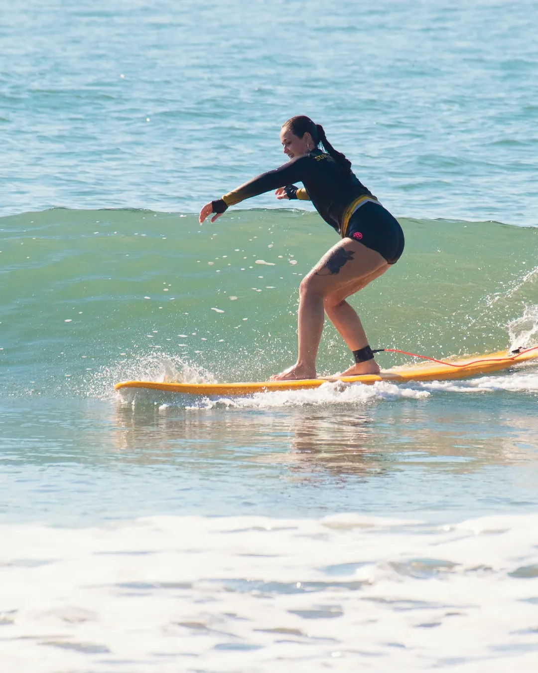 Aluna surfando durante a Imersão Village Summer na Praia do Rosa