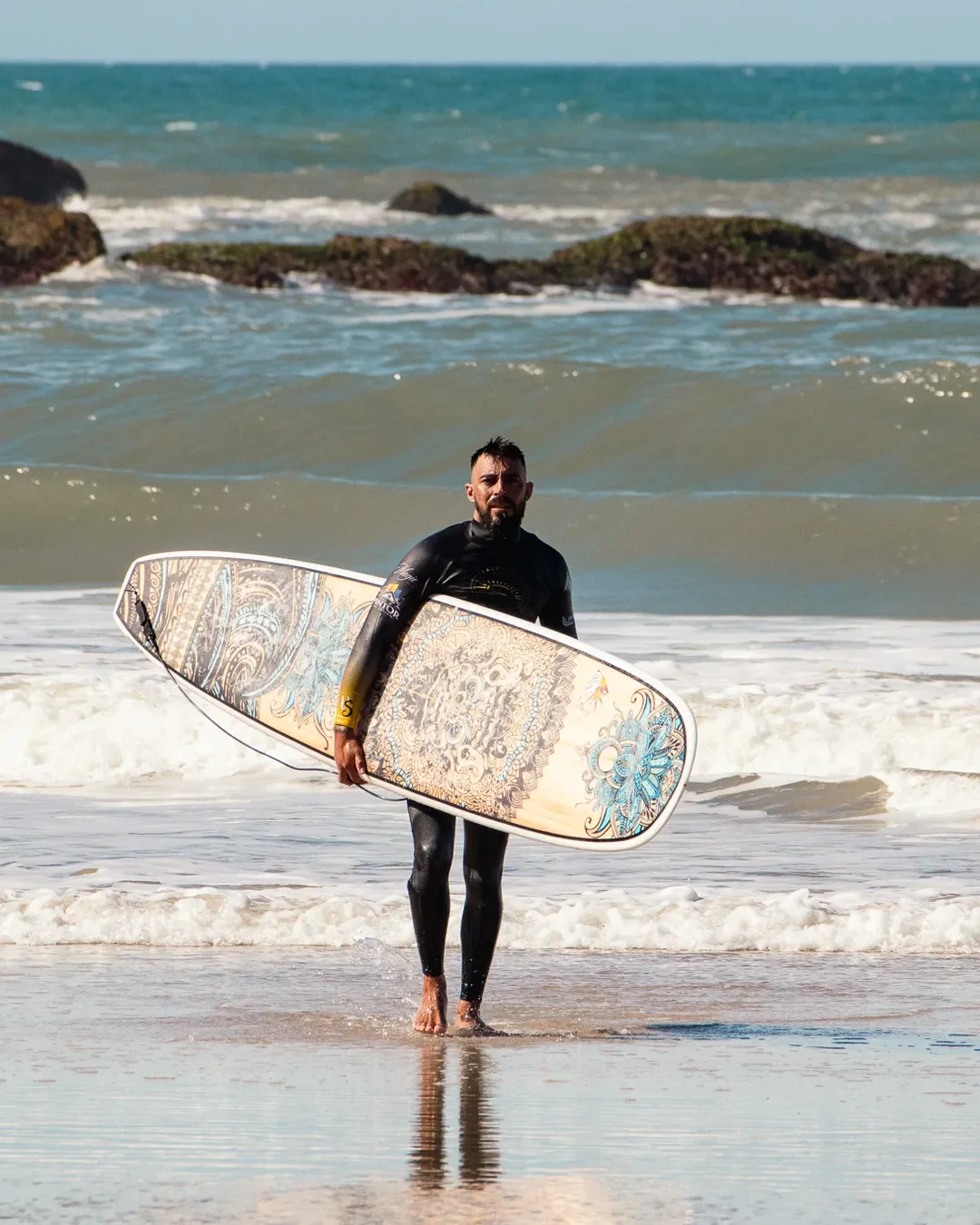Instrutor da Village Summer saindo do mar com a prancha